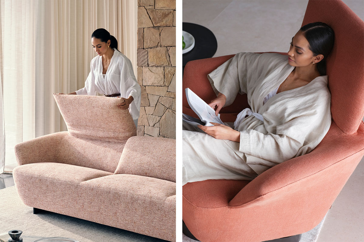 A woman adjusts the adjustable backrest of the elegantly curved Fleur Sofa and relaxe, reading a book, in the matching sculptural armchair, both finished in softly textured rose-toned fabrics.