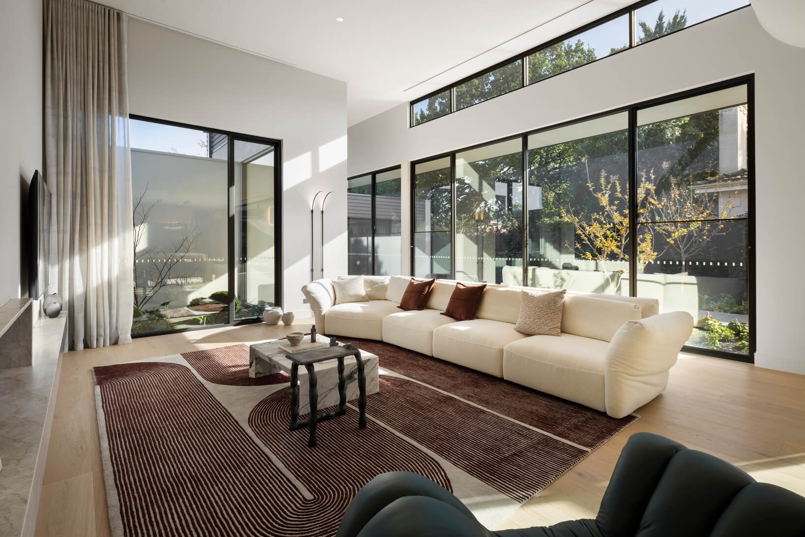 Modular sofa with keystone chaise in a light neutral fabric shapes a light-filled, open-plan living space with high ceilings.