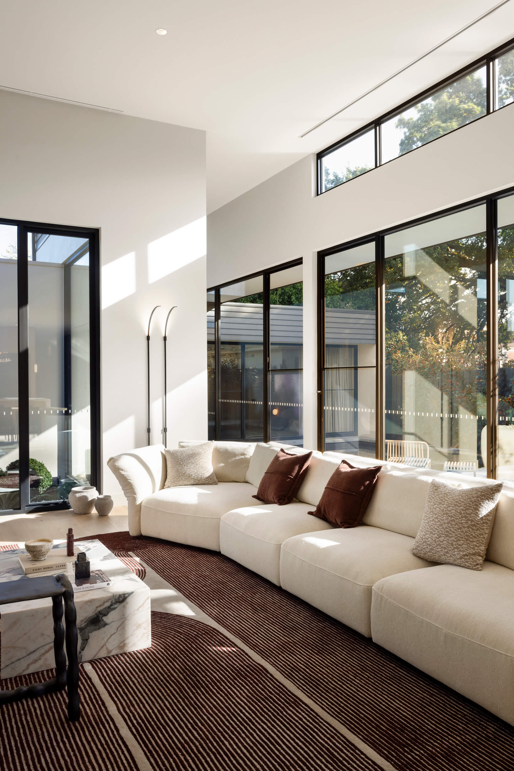 Light-filled modern living room with high ceilings and a large modular sofa with deep seats and flexible armrests.