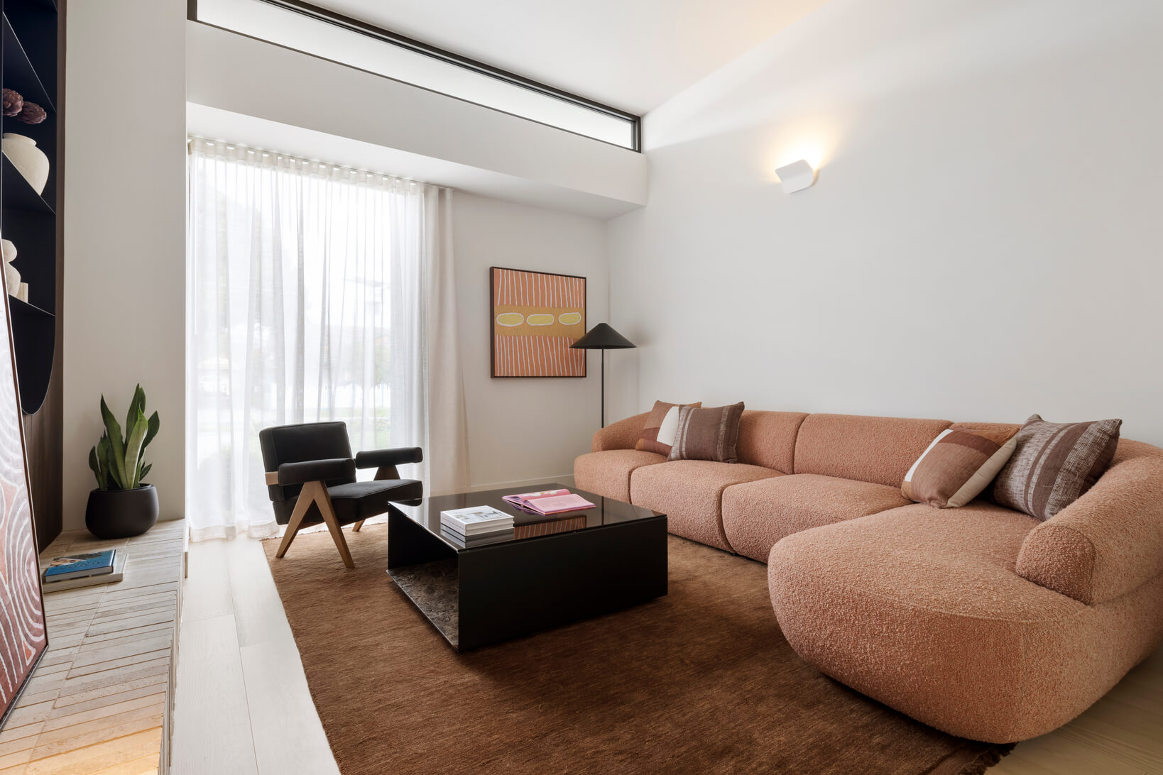 Curved modular sofa in a light pink bouclé fabric styled with Scandinavian-inspired lamps and armchair.