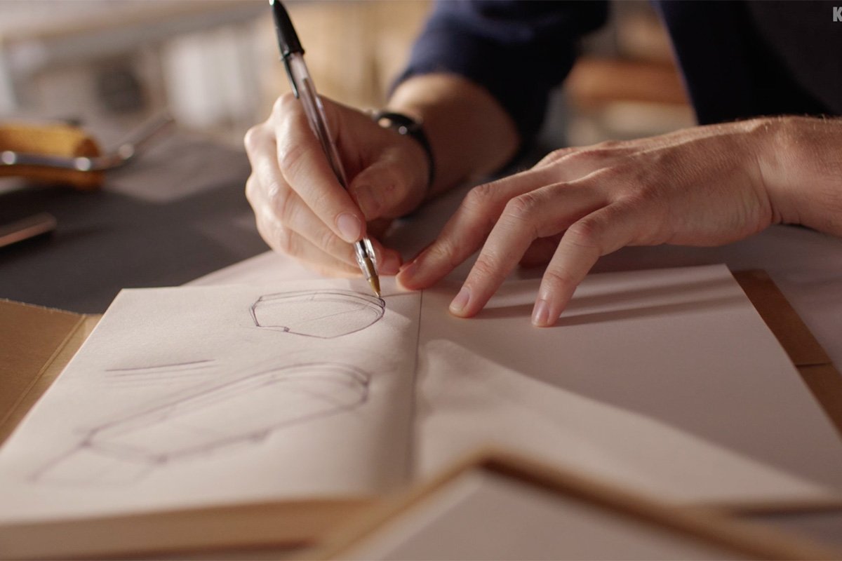 Hand sketching curved sofa designs (above). David and Chris reclined on the bolster headrest in studio setting (below).