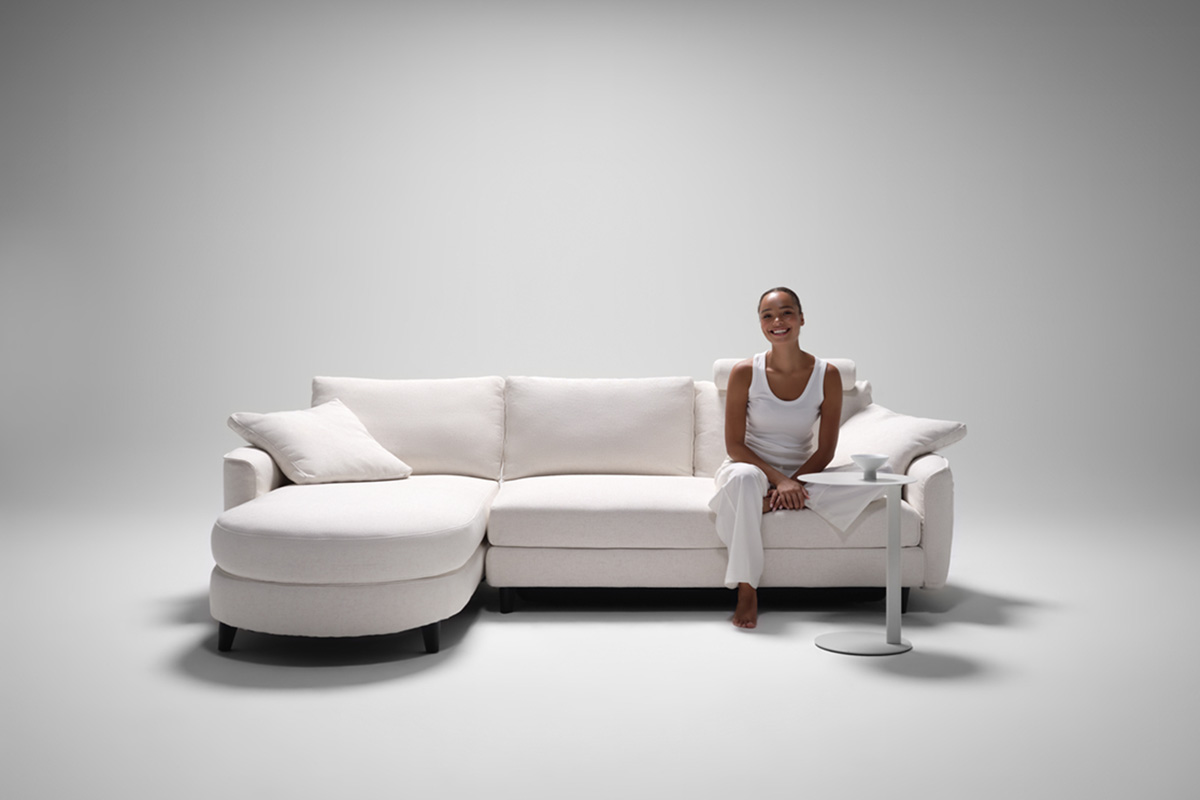 Delta 5 Modular Sofa in white fabric with a curved chaise, set in a clean, minimal and futuristic setting with a white backdrop.