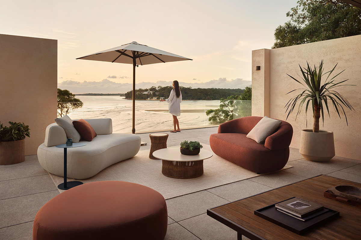 Beige and burnt orange curved outdoor furniture in an earthy colour palette, styled on a coastal terrace at sunset.