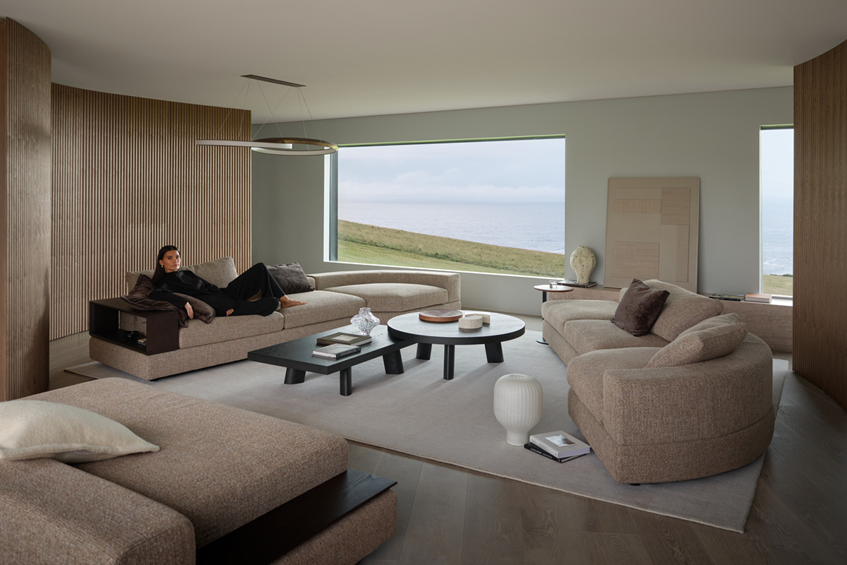 Modular curved sofa in a modern living space styled with warm mocha browns and dark timber coffee tables.