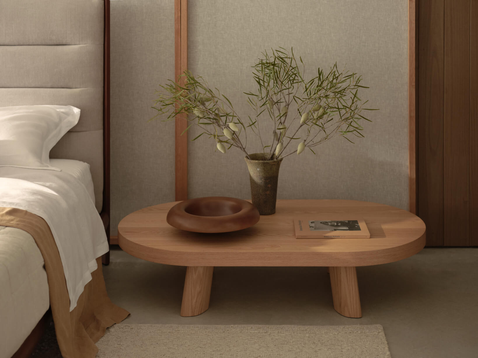A Japandi-style bedside table setup: natural oak coffee table with wooden accessories, ceramic vase and indoor plant.