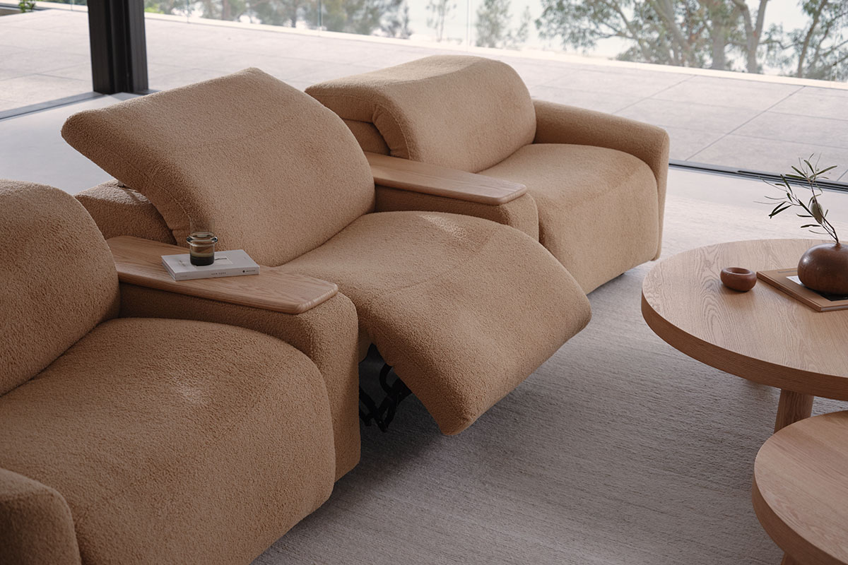 A curved reclining sofa, modular in design, with footrest and headrest extending for comfort.