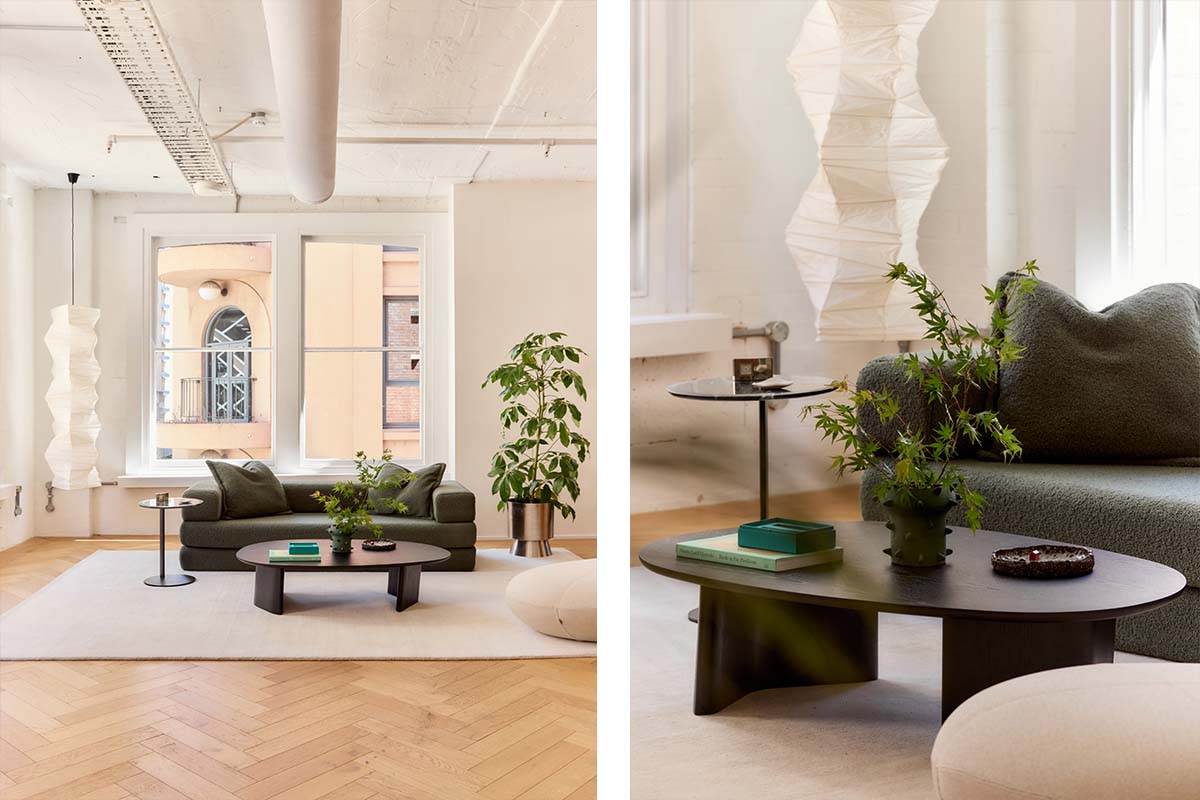 A light filled industrial loft apartment styled with a boucle sofa bed, timber furniture and houseplants.