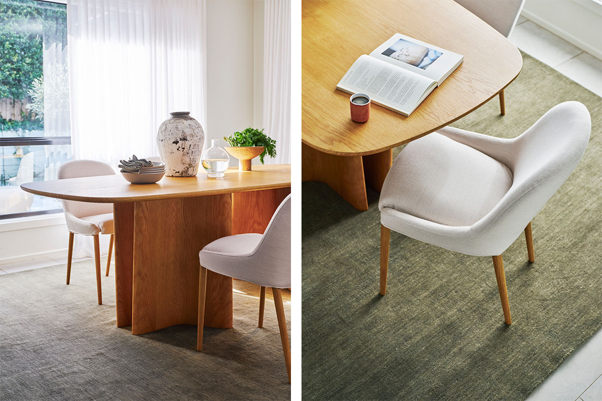 A light-filled modern dining space styled with light timber furniture, an earthy green rug, and long flowing drapes.