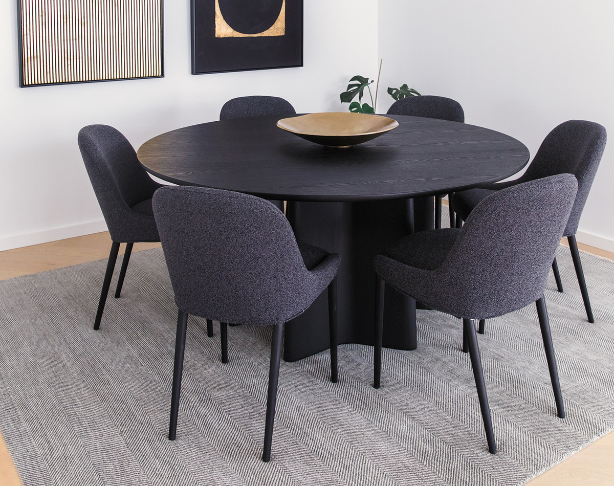 Compact corner dining setting styled with black timber furniture, a grey rug and contemporary gold décor and artwork.
