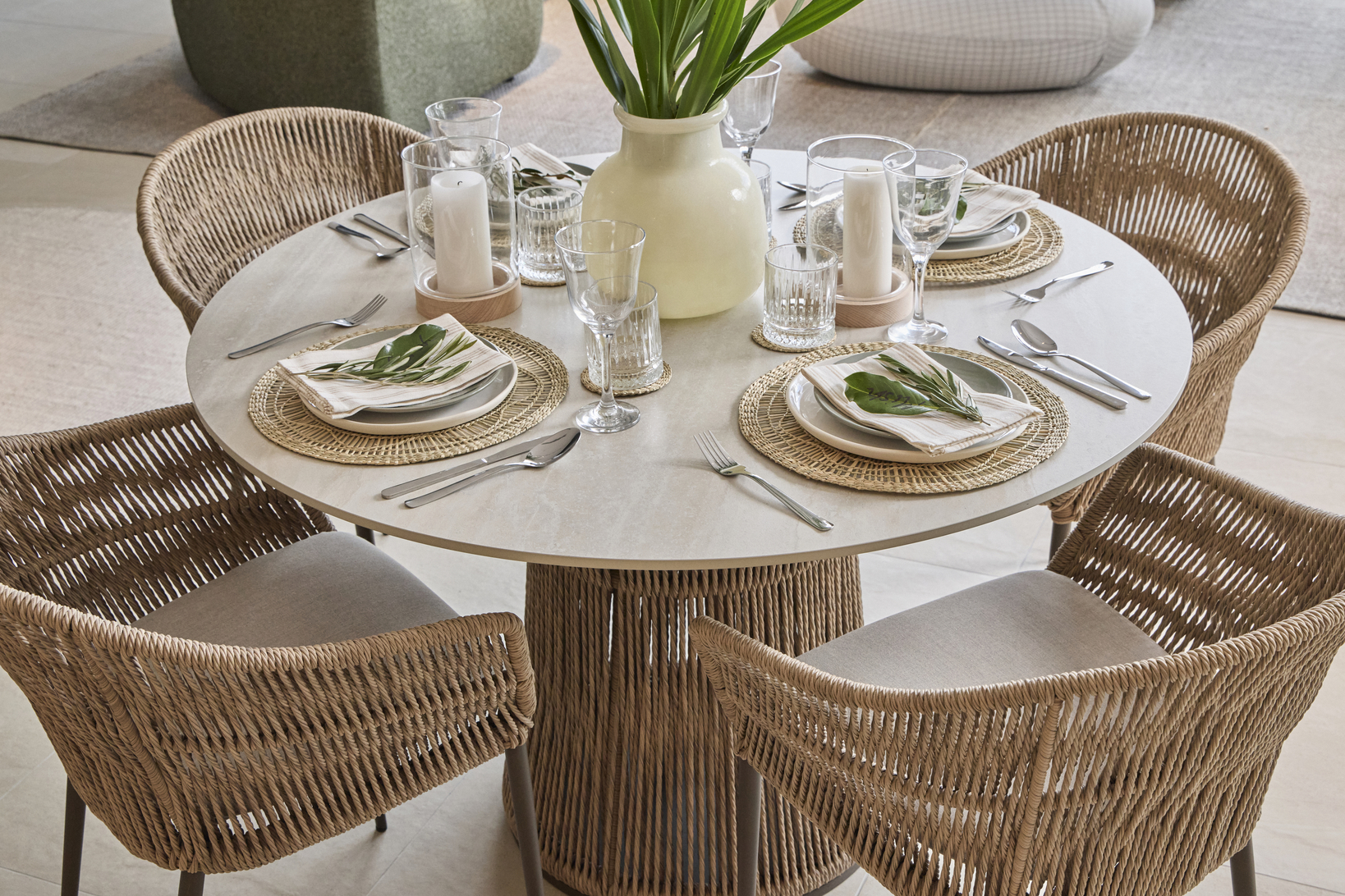 Woven dining chairs and outdoor table styled in an earthy setting with rattan placemats, linen napkins and eucalyptus leaves.