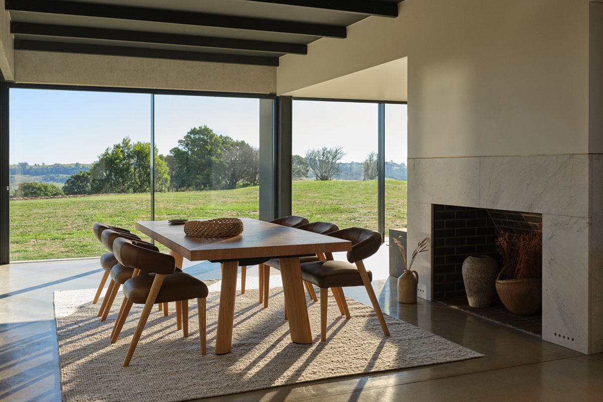 Contemporary dining space with light oak furniture opening out to views of greenery.