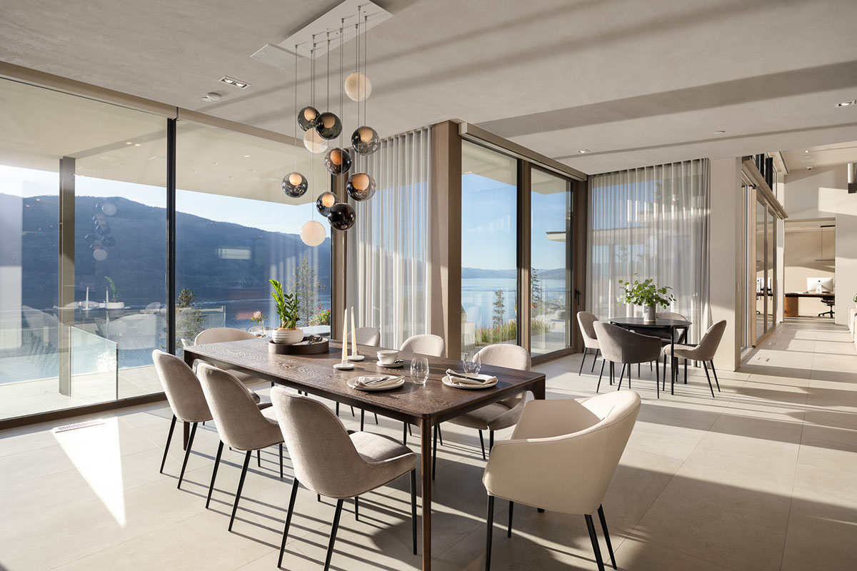 A light-filled modern open-plan dining space with mountain views, a timber dining table and leather and fabric dining chairs.