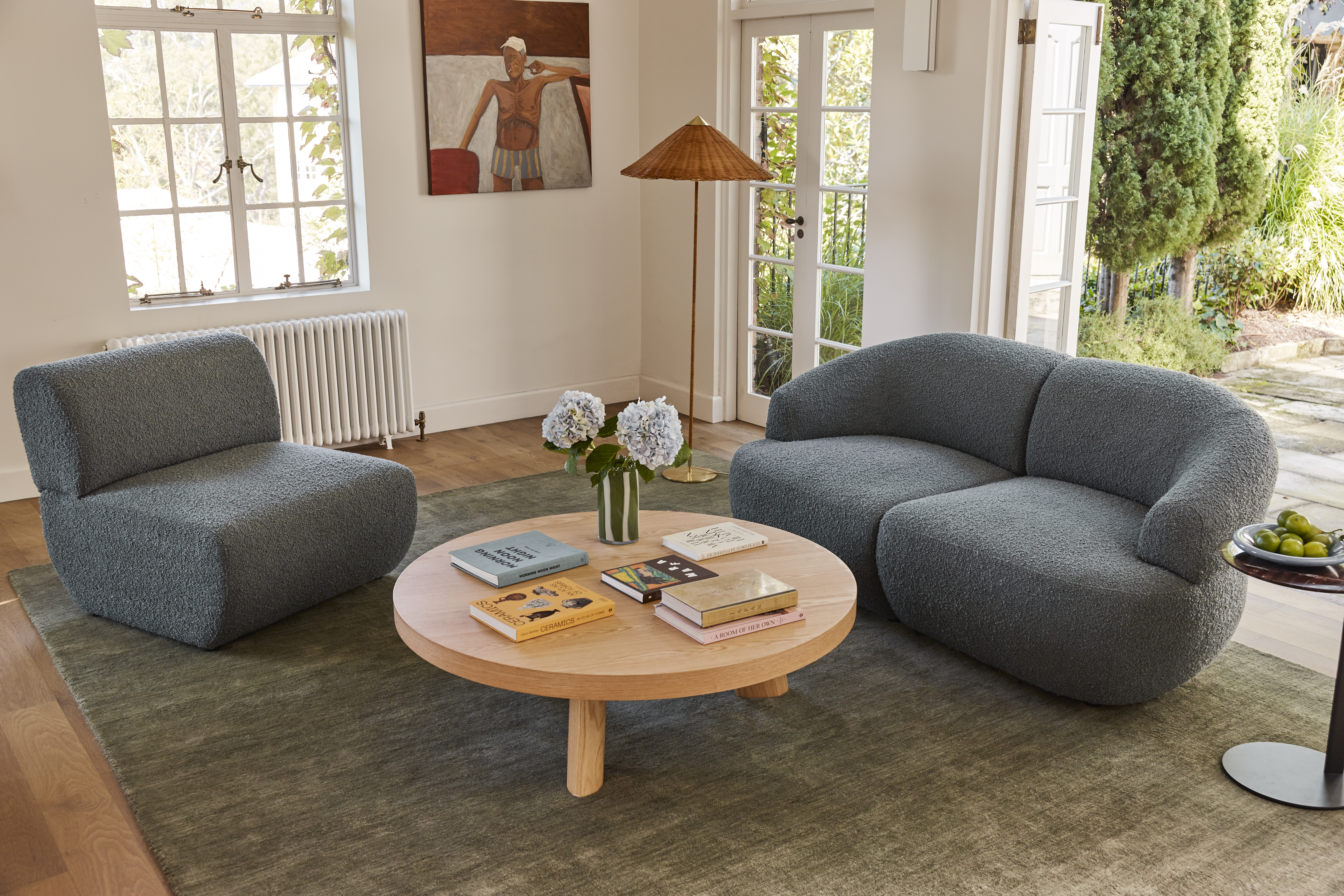 A camel-toned modular sofa complemented by a tonal accent chair, rug and coffee table in a light-filled contemporary living space.