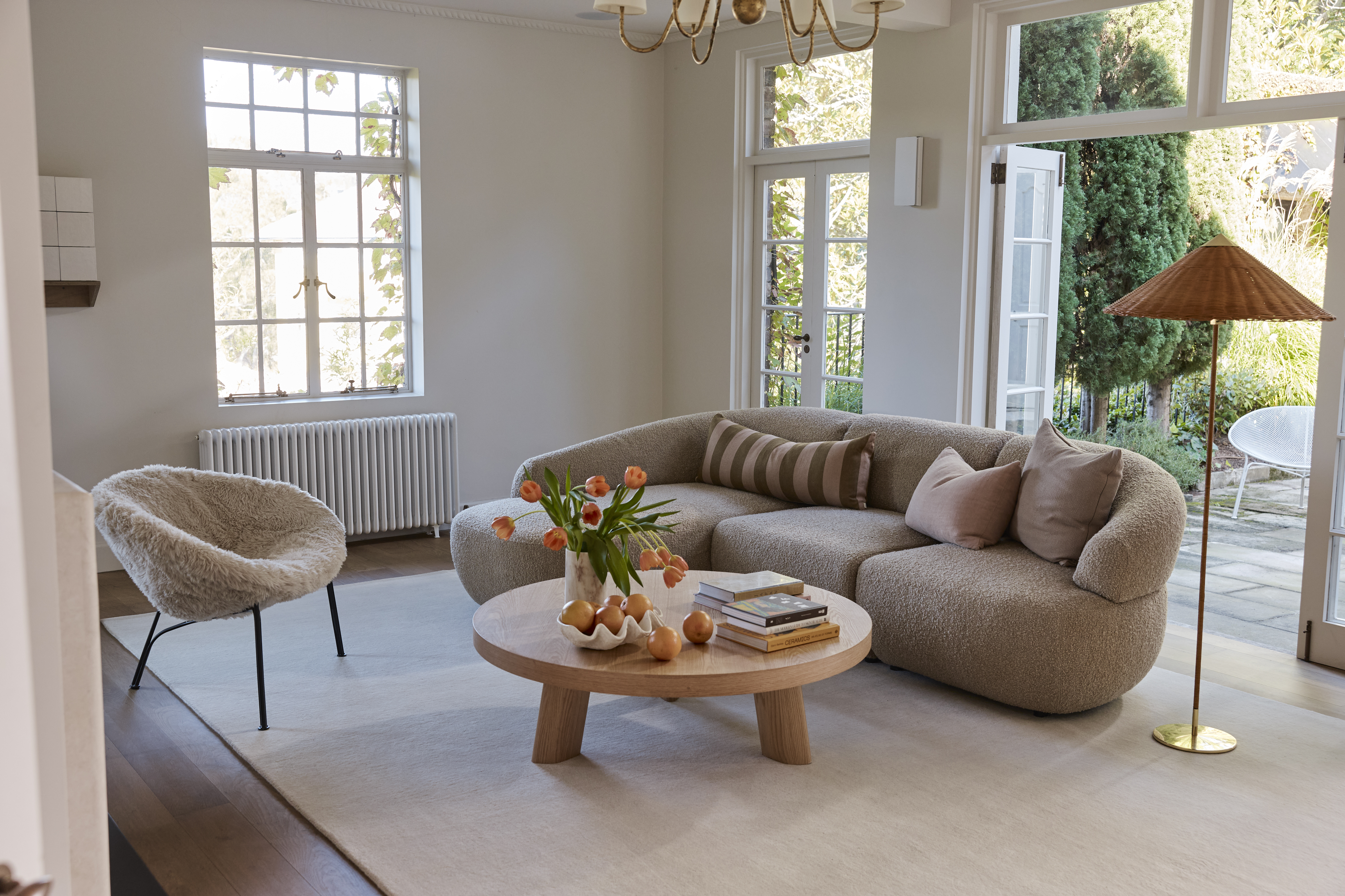 A camel-toned modular sofa complemented by a tonal accent chair, rug and coffee table in a light-filled contemporary living space.