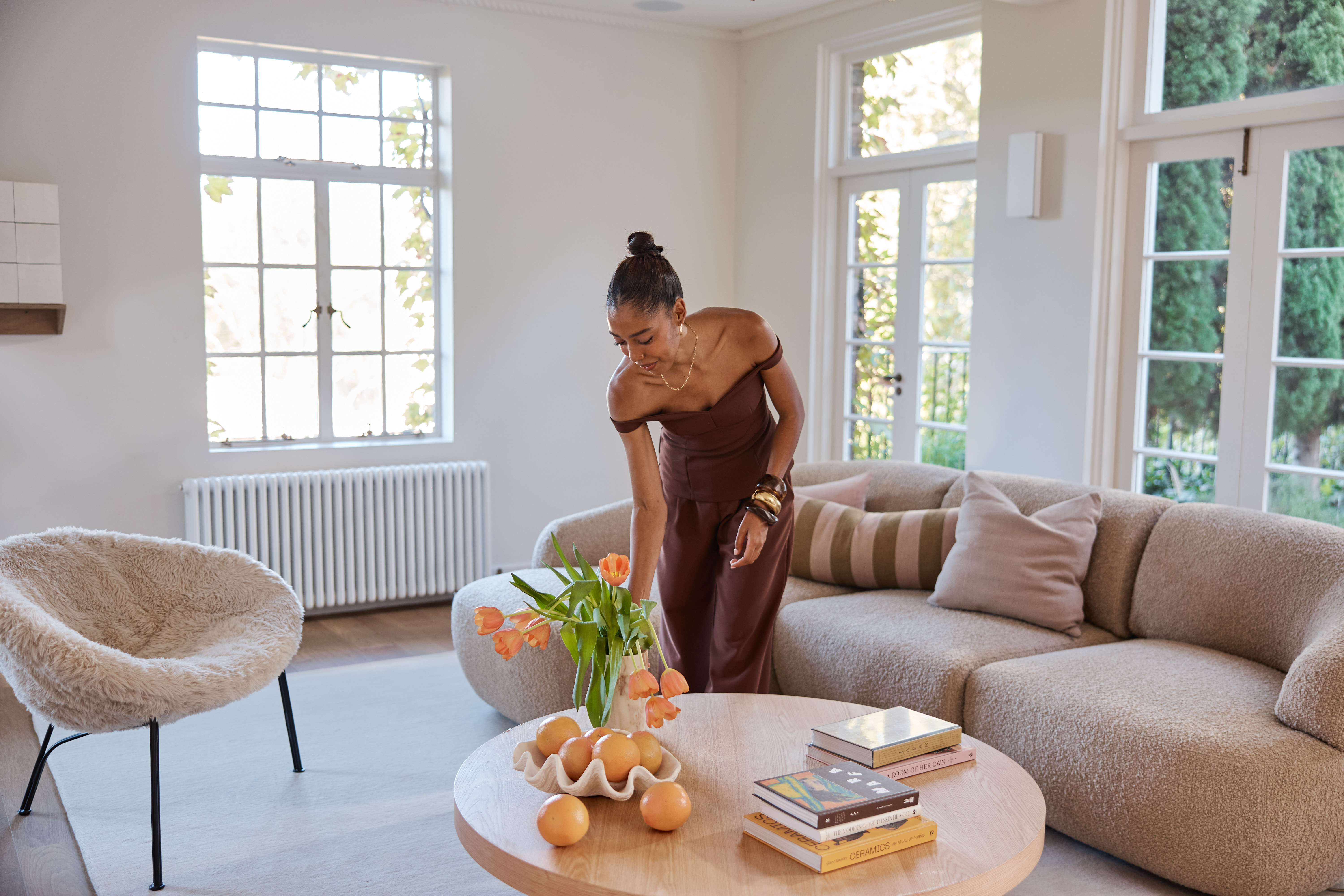 Elegant woman places a vase of flowers on a coffee table in a small living room