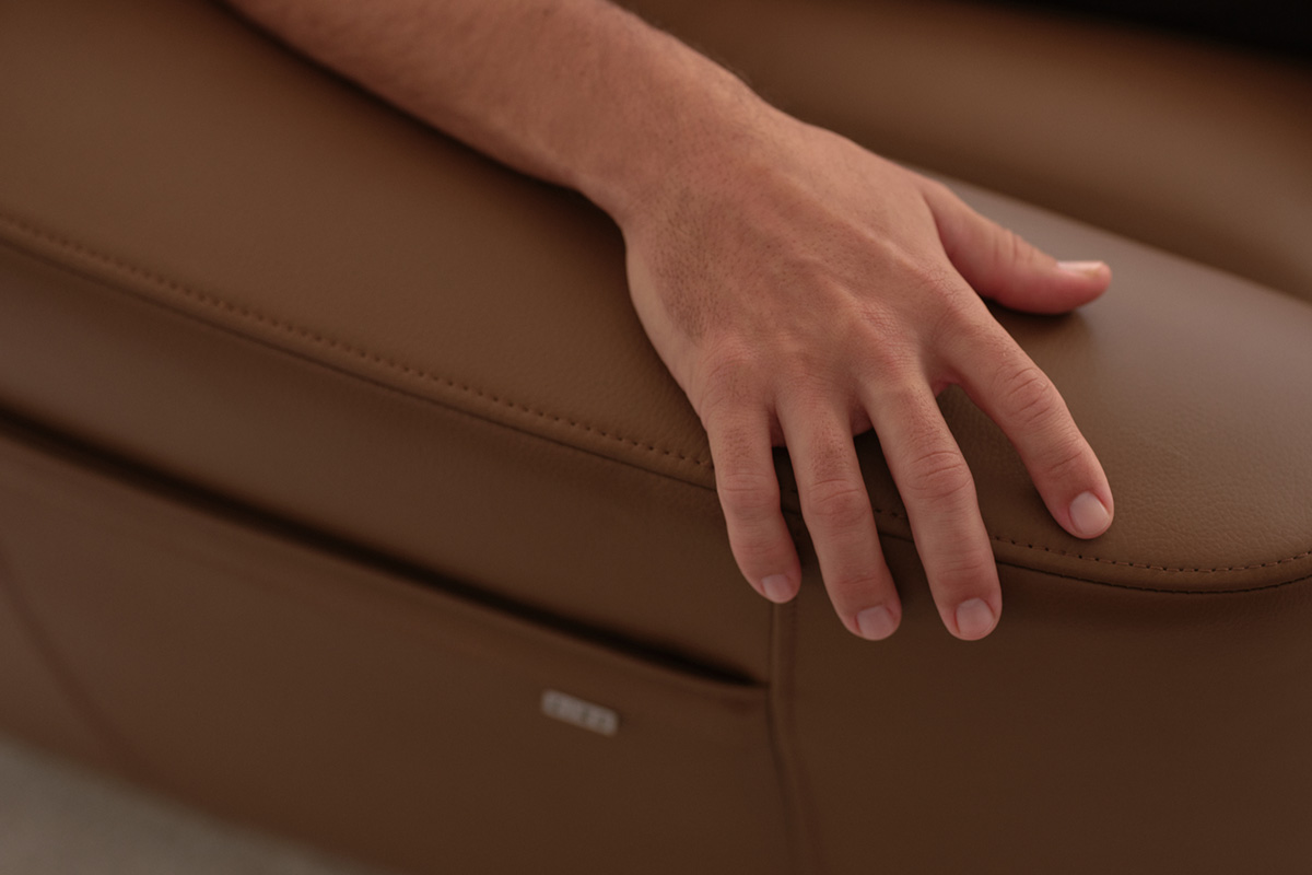 A contemporary recliner sofa finished in a luxurious brown leather and smart accessories in a home cinema room.