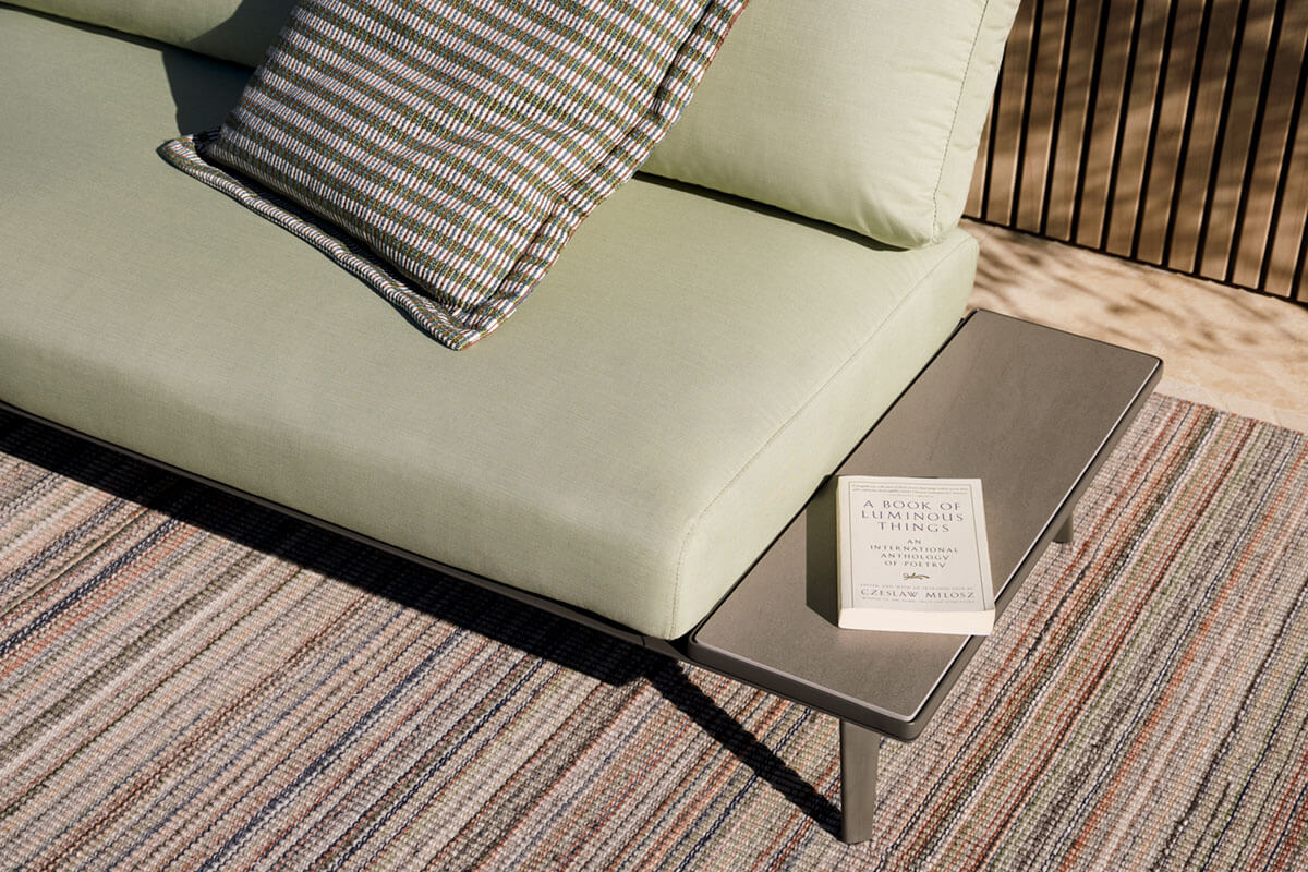 Outdoor sofa shifting from daybed to chaise styled in high-performance outdoor sage green fabric.