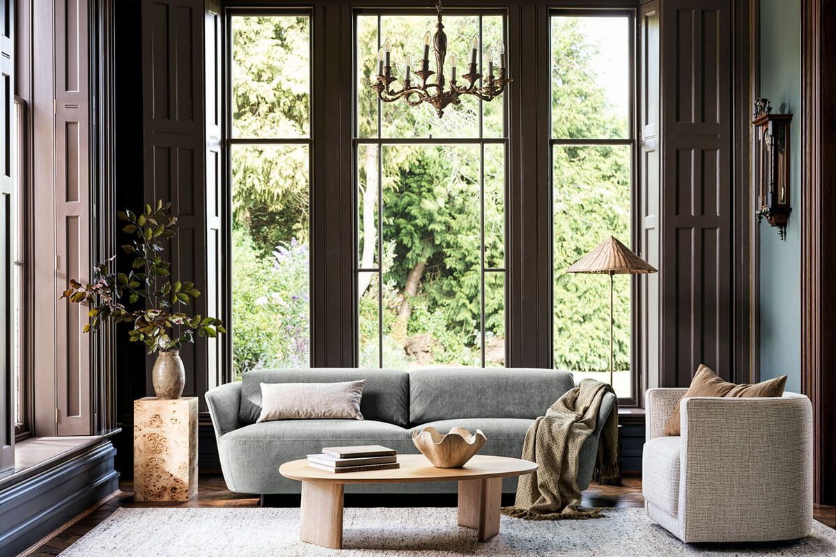 Classic architectural interior with a modern, sage textured weave sofa against expansive windows and layered soft neutrals.