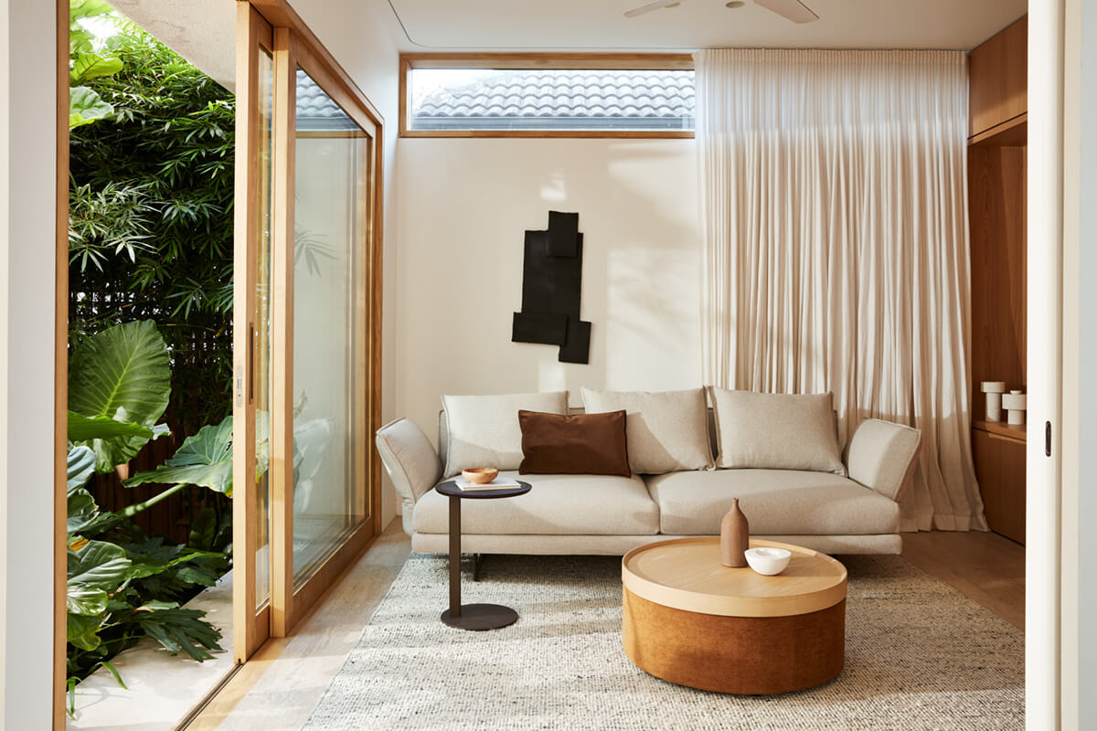 Textured fabric and leather swatches, with a bright indoor-outdoor living space featuring a neutral sofa and warm accents.