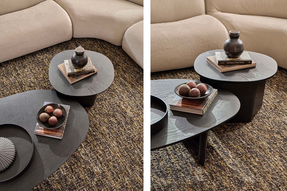 A layering of two black, organic-shaped coffee tables in a monochromatic living room, styled with neutral high back sofas.