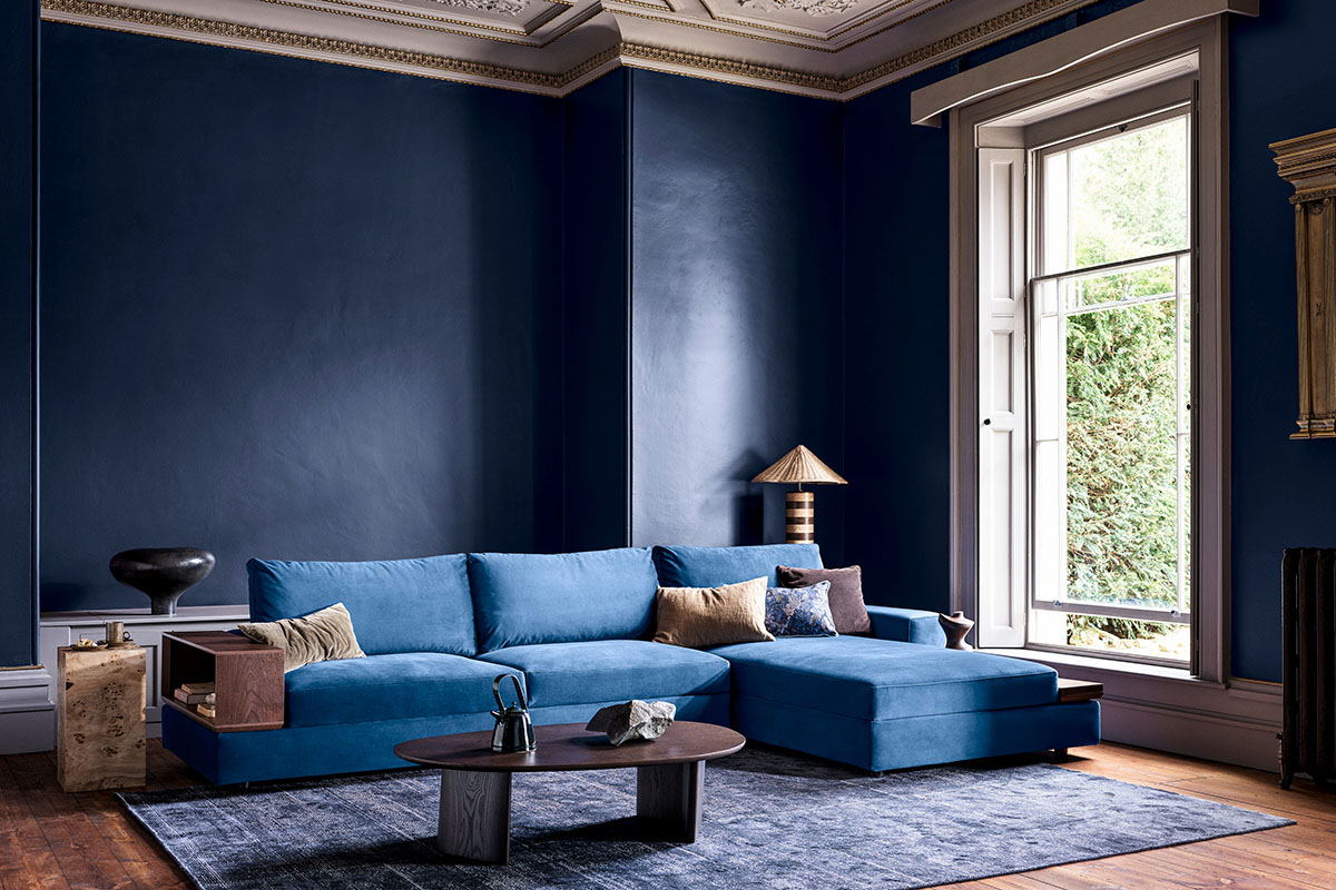 Velvet blue sofa in a modern living room with high ceilings and minimal decor.