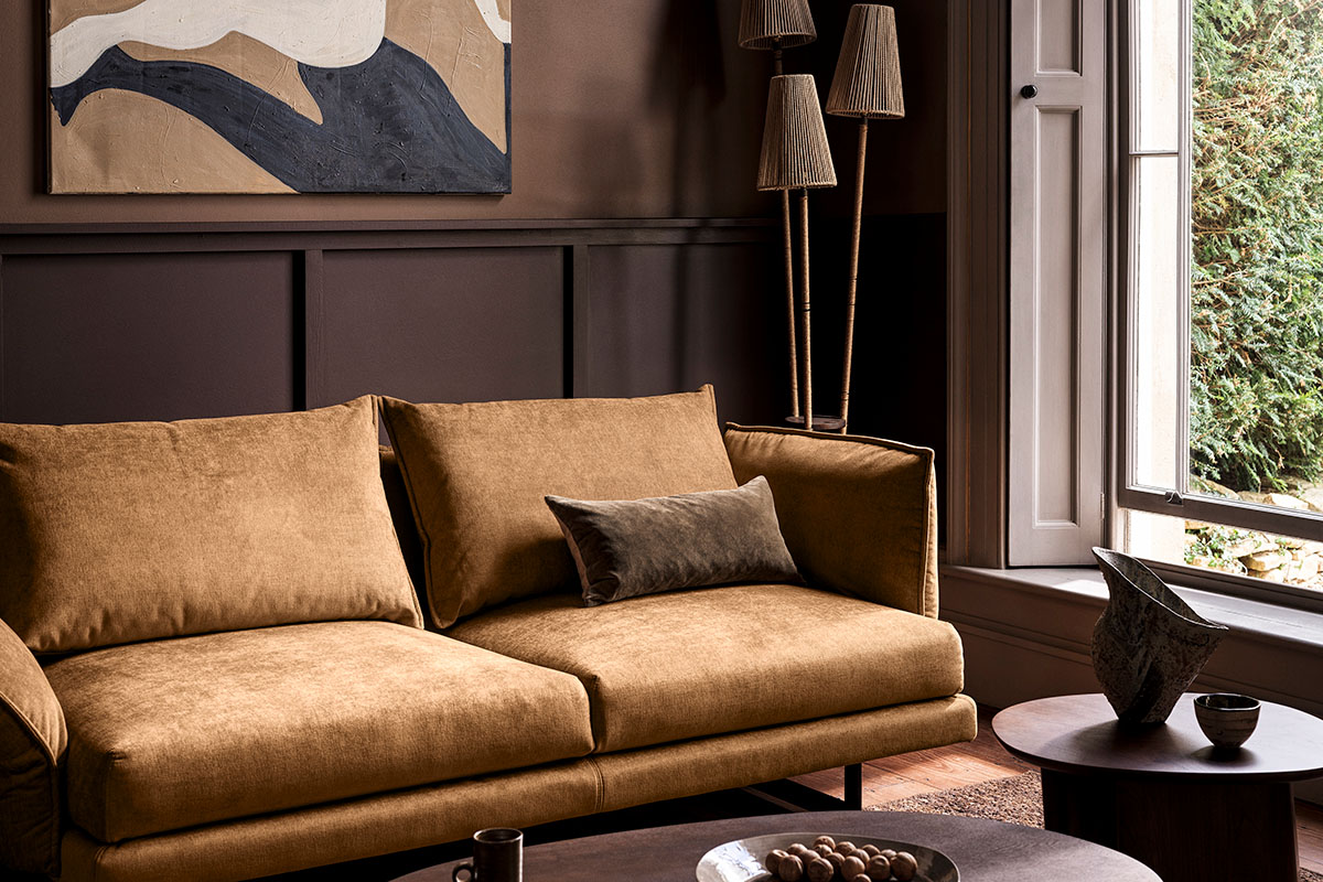 Golden fabric sofa in a modern living room, styled with minimal decor and large artwork.