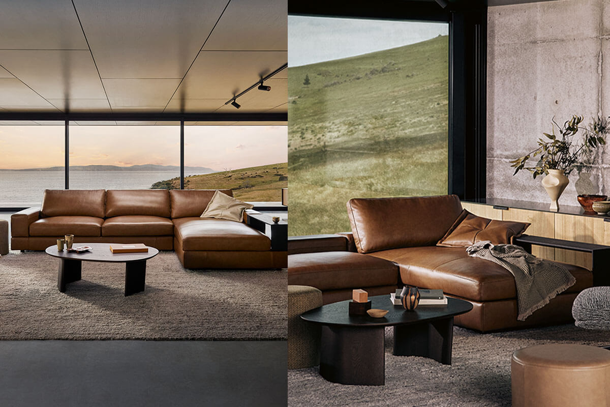 Modular L-shaped sofa with chaise in rich tan leather styled with charcoal-toned tables and layered neutrals, set against landscape views.