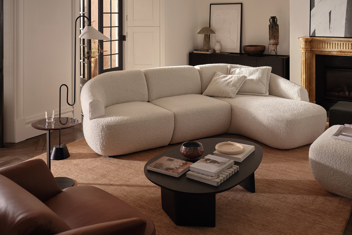 The Aura modular sofa styled as an L-shaped sofa with chaise, in a neutral bouclé fabric in a modern living room.