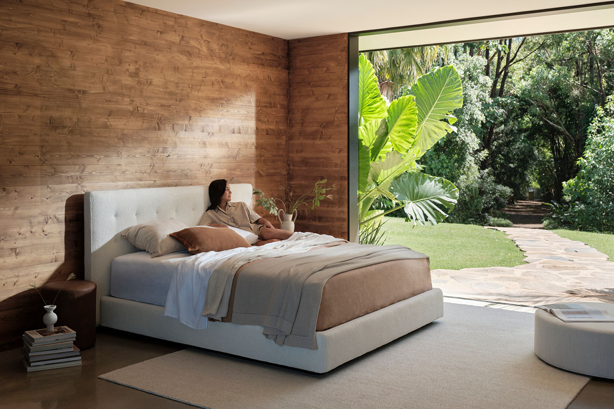 Bedroom styled with timber walls, soft rustic blush and neutral bedding, and organic textures layered with woven and wool finishes.
