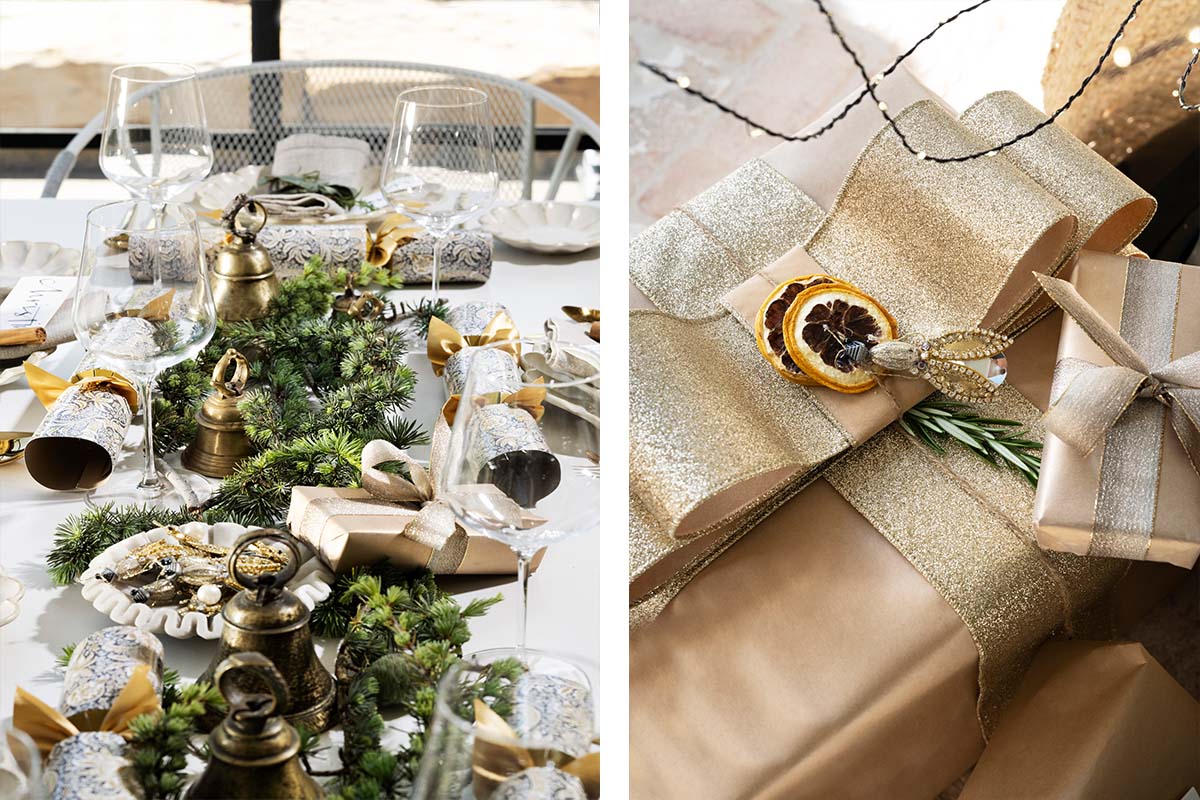 A festive table featuring gold candleholders, greenery runner, metallic ornaments, and gift wrapping with gold and silver ribbons.