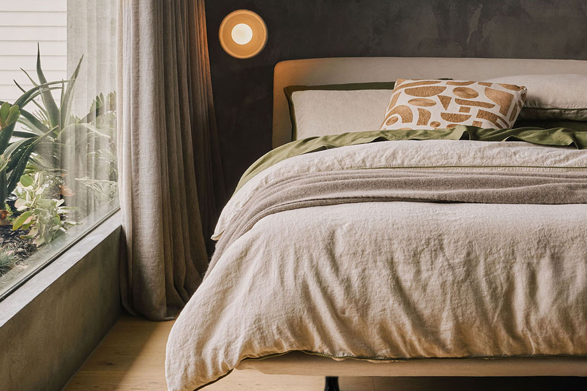 A guest bedroom featuring a layered bed in soft neutral tones beside a large window.