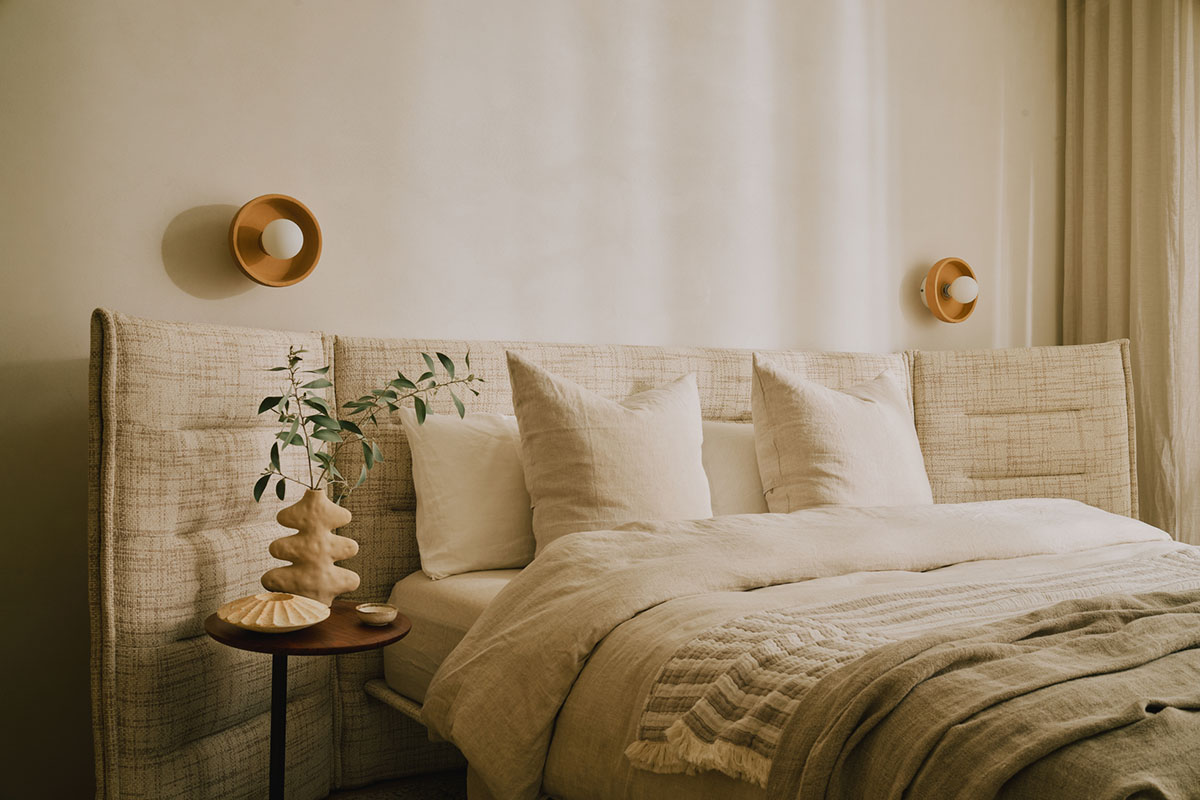 A queen size bed with channelled side panels offering privacy and comfort in a neutral guest bedroom.