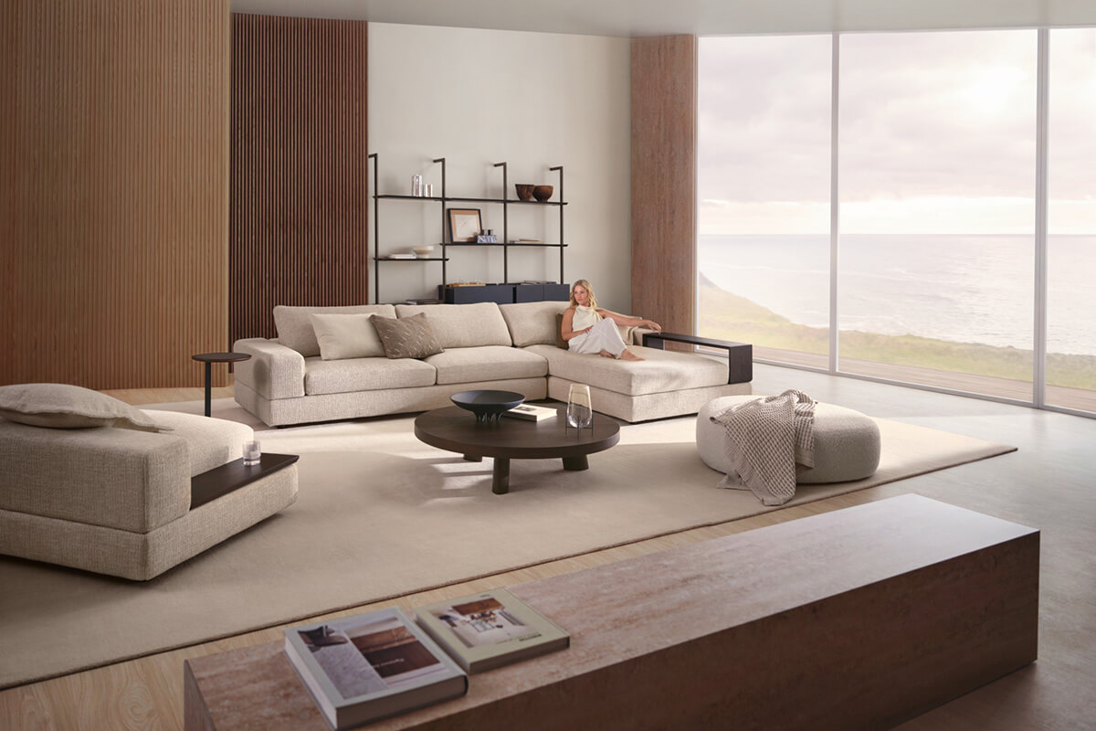 A Scandinavian-inspired living room with timber walls, sideboards, a light neutral modular sofa, rug and expansive windows to views.