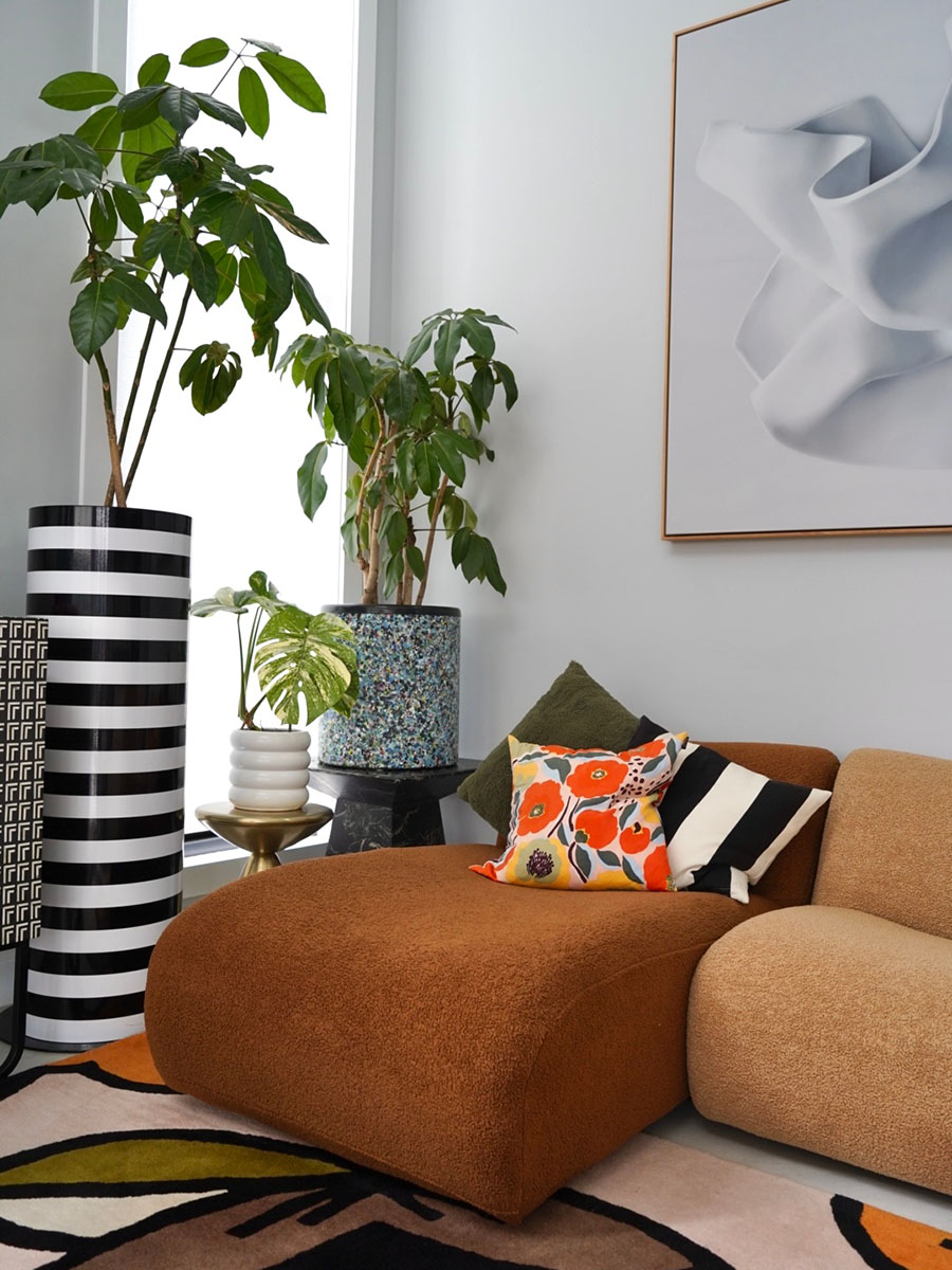 A shot highlighting the chaise module of the 1977 Sofa, accented with layered cushions, bold pattern and vibrant indoor greenery.