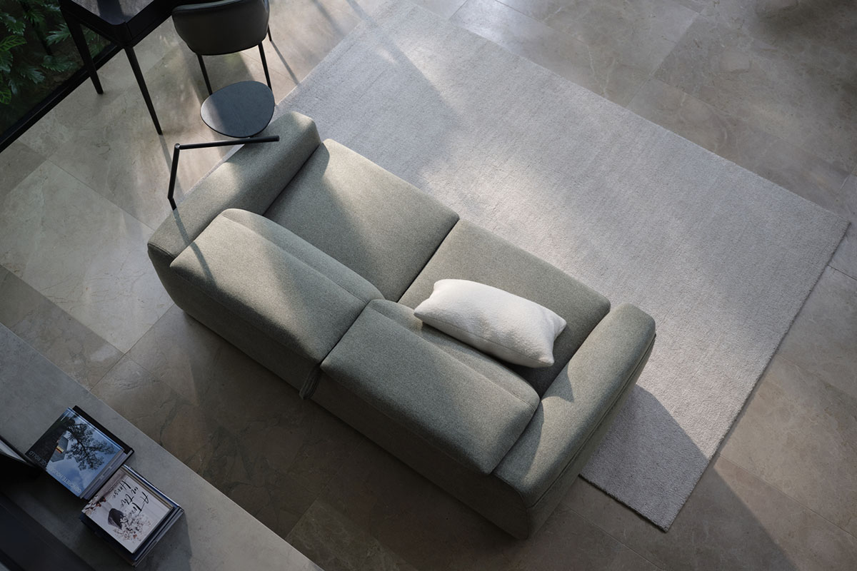 Top view of a sleek, modern sofa in a spacious, minimalist living area with natural light and neutral tones.